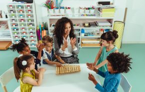 Teacher helping cheerful children playing some musical toys at kindergarten