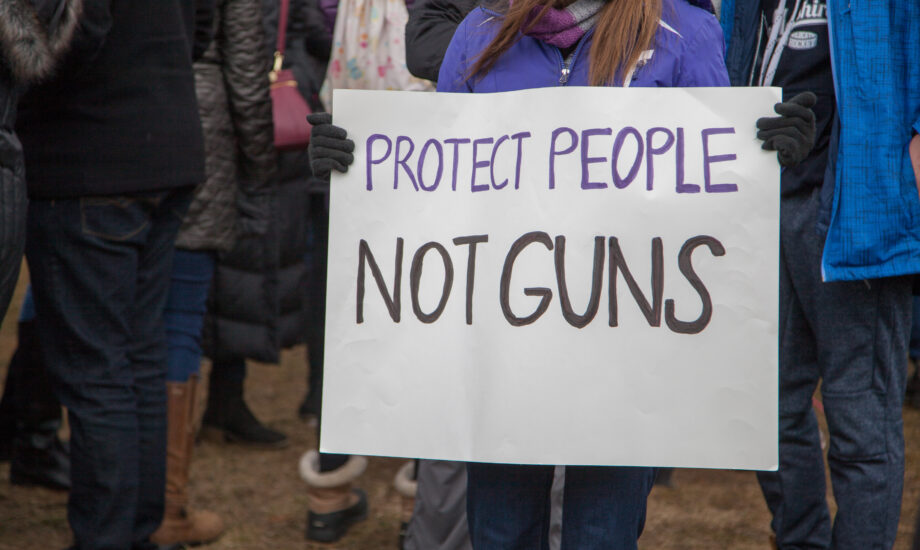Person holding protest sign that says, "Protect people, not guns"