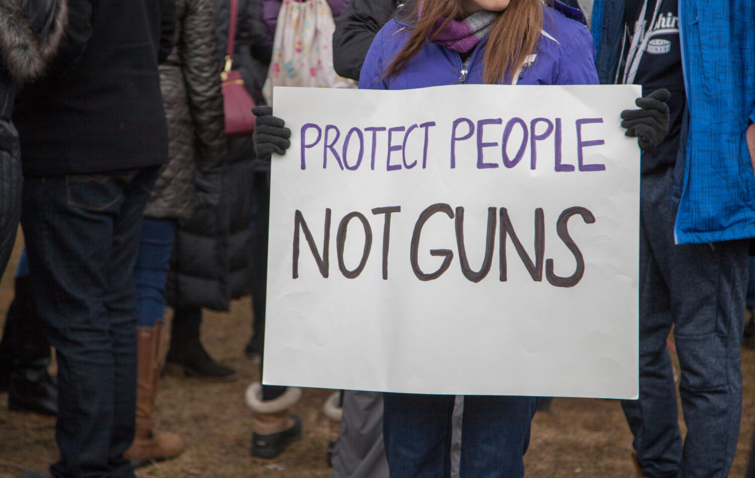Person holding protest sign that says, "Protect people, not guns"